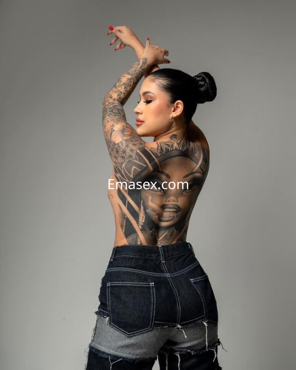 Puta con cabello recogido y tatuajes visibles en la espalda, usando pantalones de mezclilla en Vitoria.