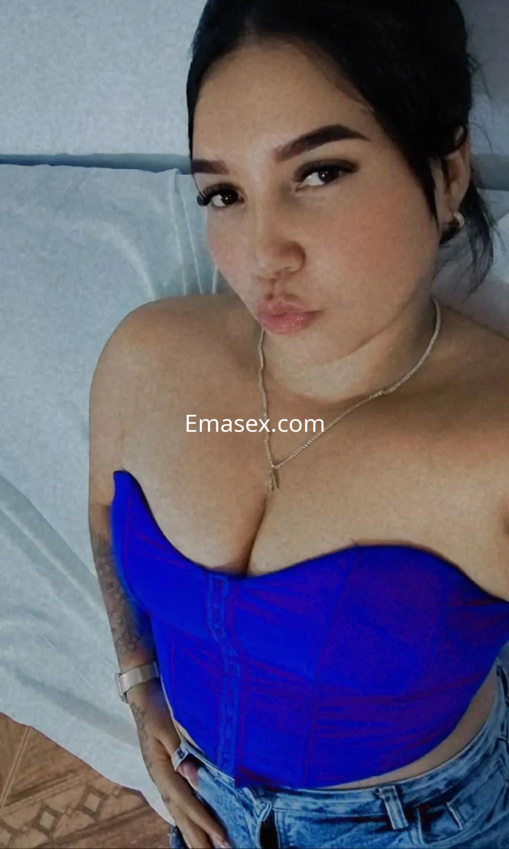 Escort en Córdoba posando con un top azul ajustado y jeans, luciendo un maquillaje sutil y expresión coqueta.