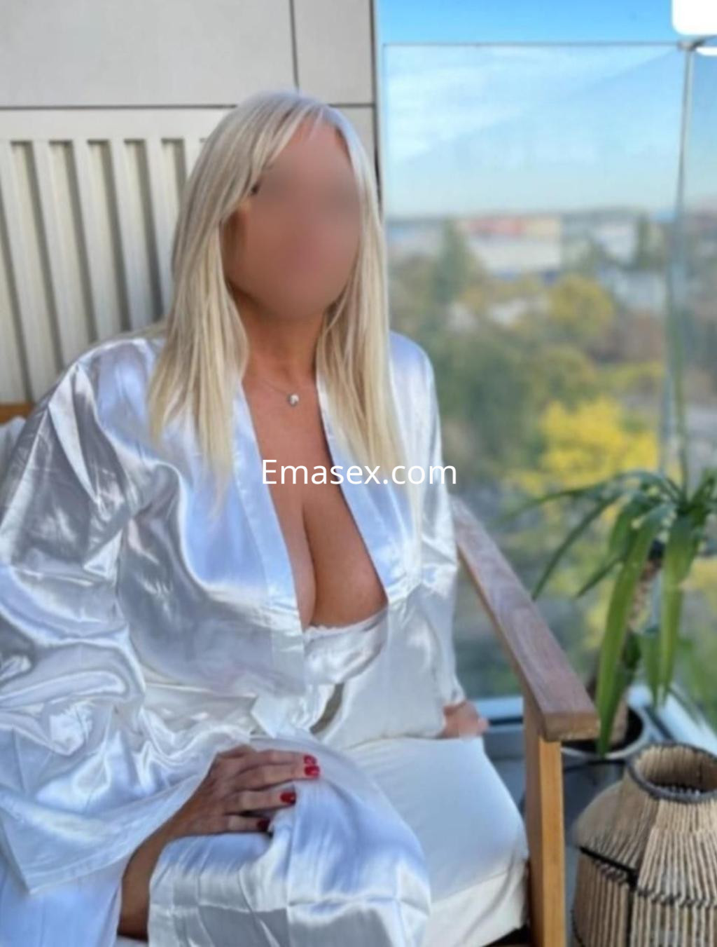 Puta con cabello rubio y lacio, vestida con un kimono blanco, sentada en un sillón con vista a la ciudad de Lugo.