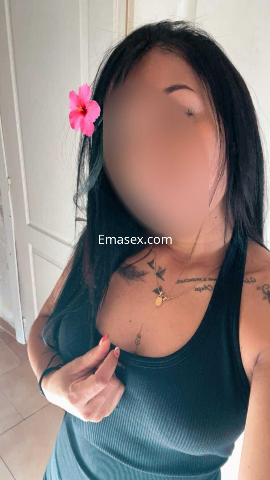 Escort en Madrid con cabello largo y lacio, vistiendo una camiseta negra y adornada con una flor.