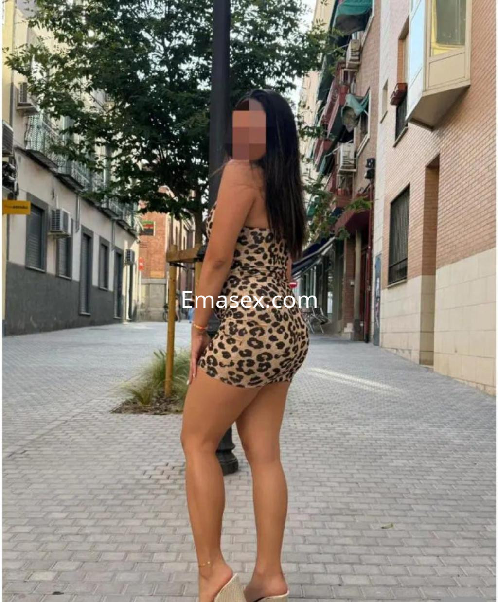 Puta en Pamplona vistiendo un ajustado vestido de leopardo, posando de espaldas en una calle urbana.