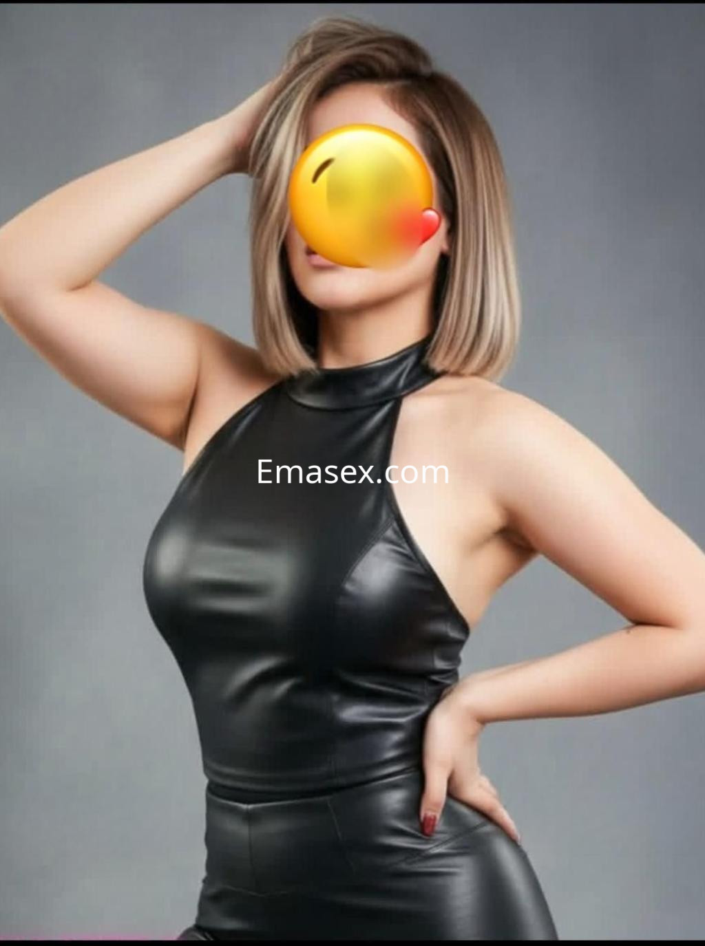 Escort en Ibiza viste un ajustado vestido de cuero negro, con cabello corto y rubio, posando de lado.