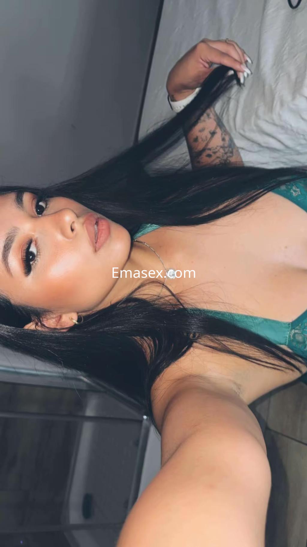 Escort en Vitoria con cabello largo y oscuro, luciendo un conjunto de lencería verde mientras posa en una habitación.