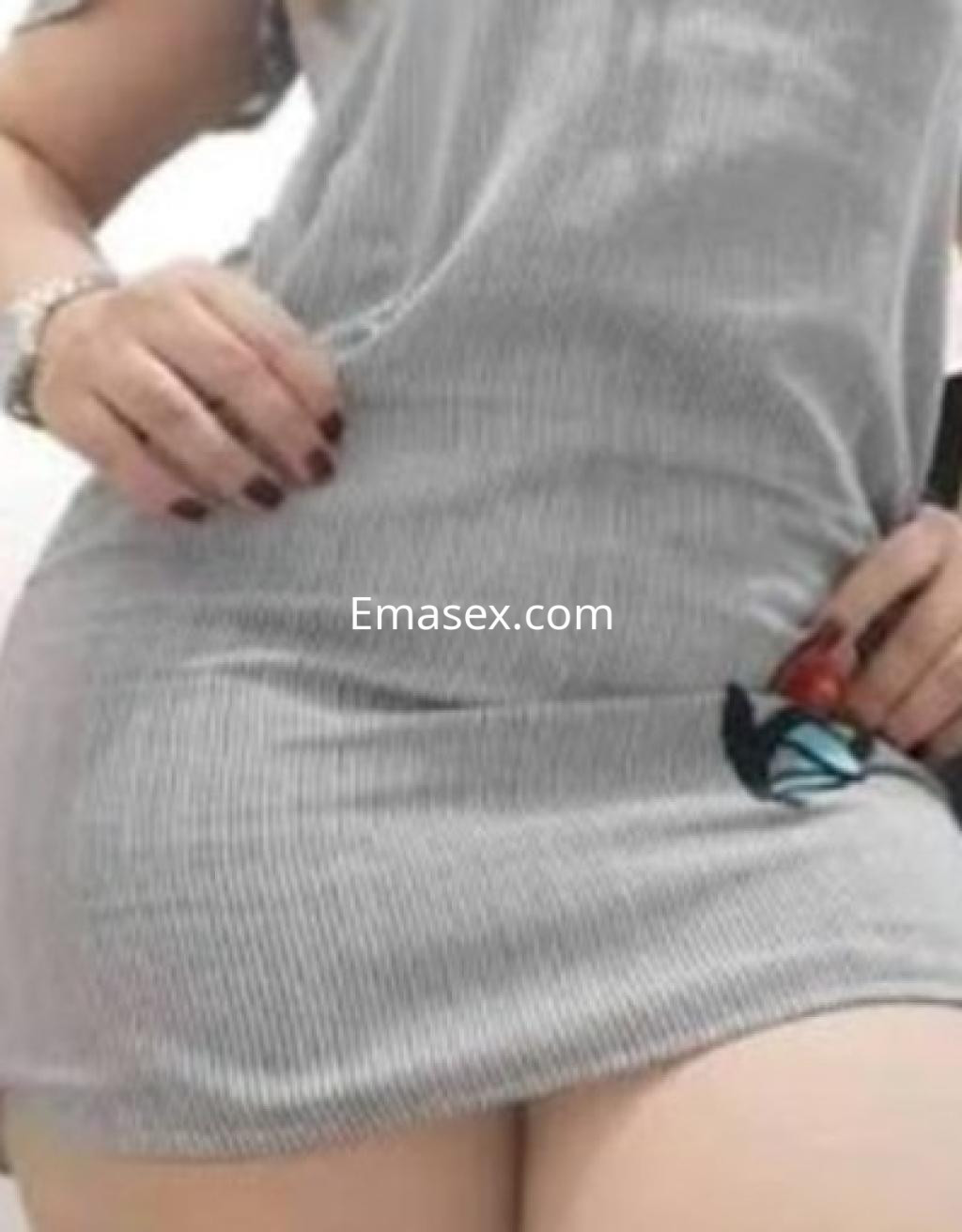 Escort en Córdoba viste un vestido gris ajustado con detalles de mariposa, mostrando parte de su figura.