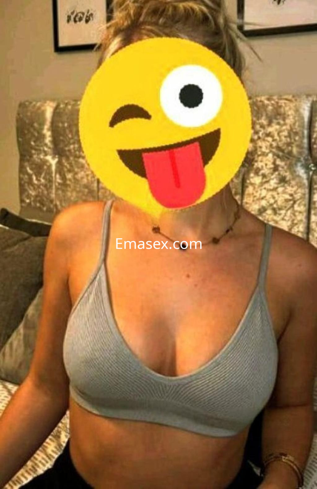 Puta con top gris y collar, sentada en un sofá, en un ambiente acogedor de Córdoba.
