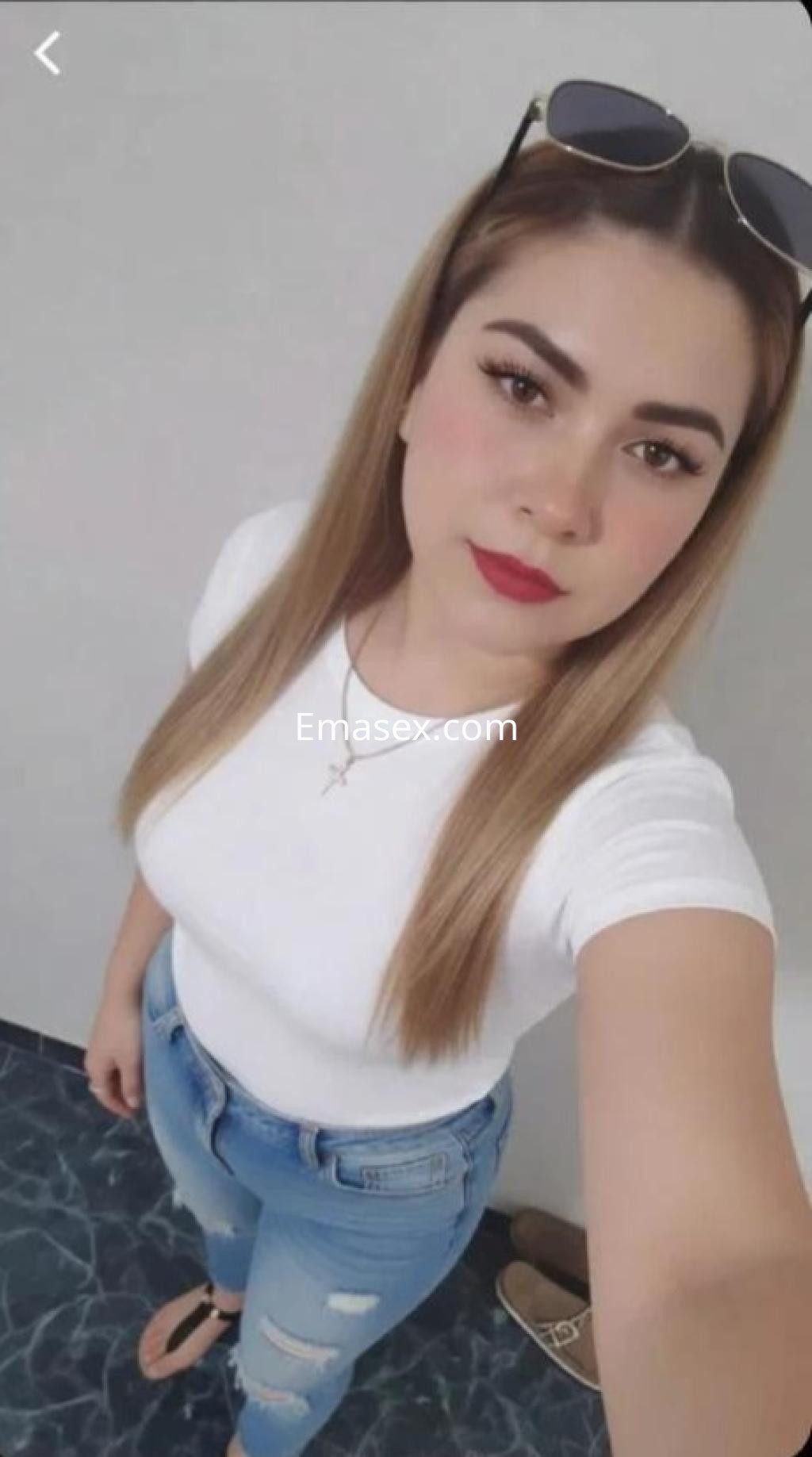 Puta en Zamora posa con camiseta blanca y jeans ajustados, luciendo cabello lacio y lentes de sol.