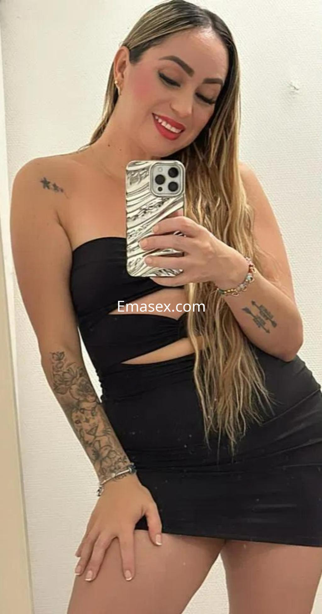 Puta en Barcelona con vestido negro ajustado, cabello largo y lacio, sonriendo mientras toma una selfie.