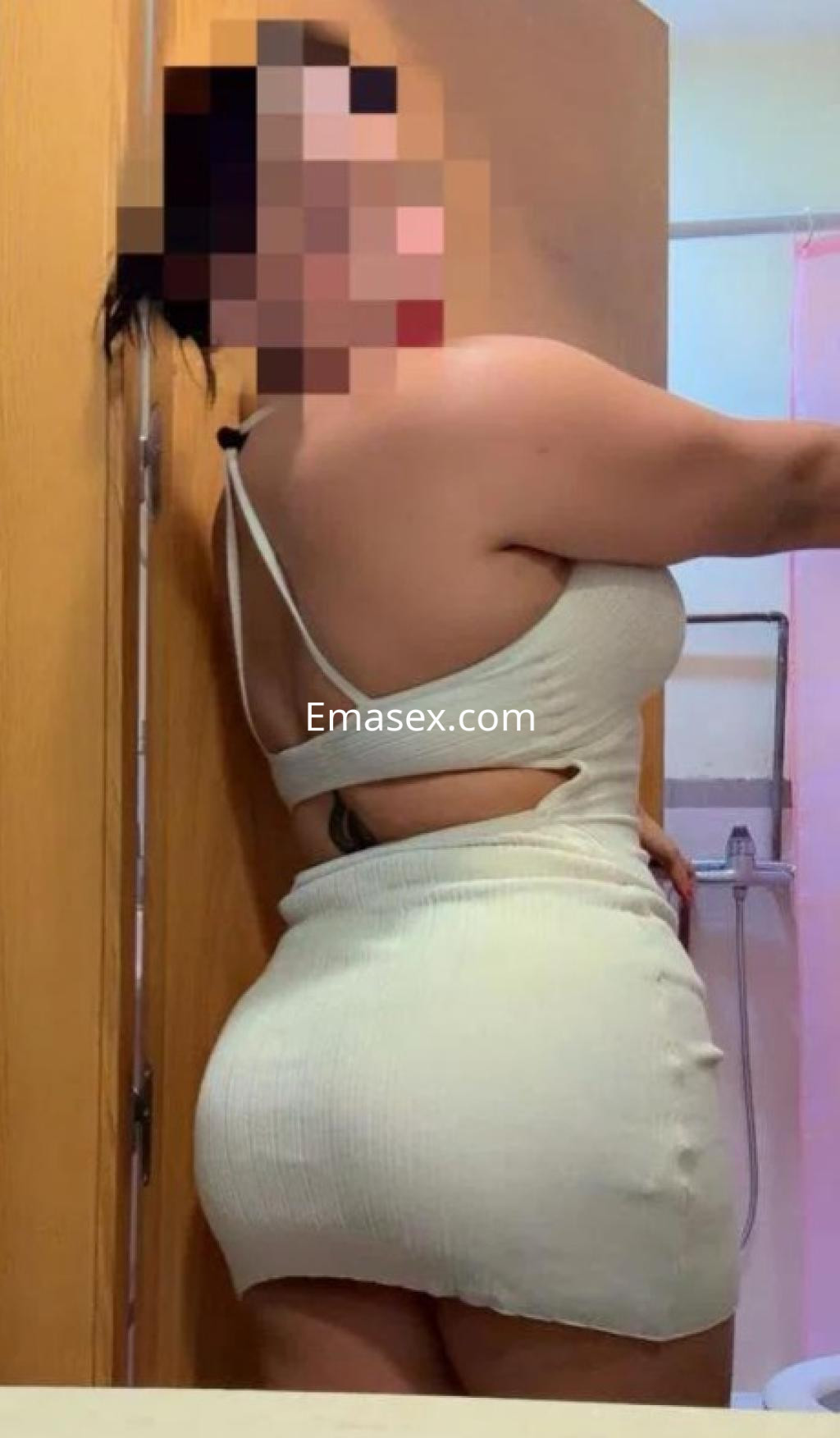 Puta de Castellón posando de lado en un vestido ajustado y corto, mostrando su figura en un ambiente interior.