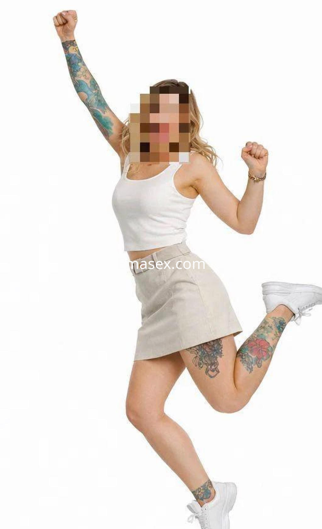 Escort en Granada con blusa blanca y falda corta, mostrando sus tatuajes mientras salta alegremente.