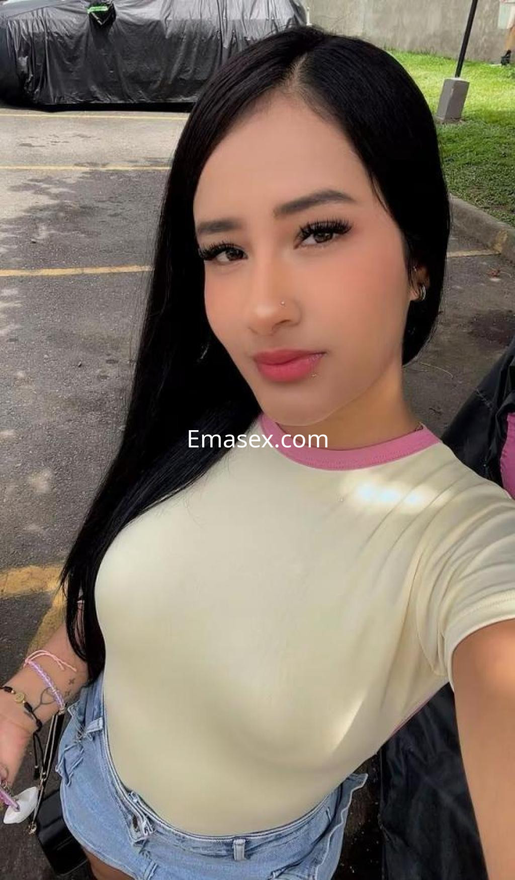 Escort en Madrid con cabello largo y lacio, lleva una camiseta amarilla y shorts de mezclilla, sonriendo a la cámara.