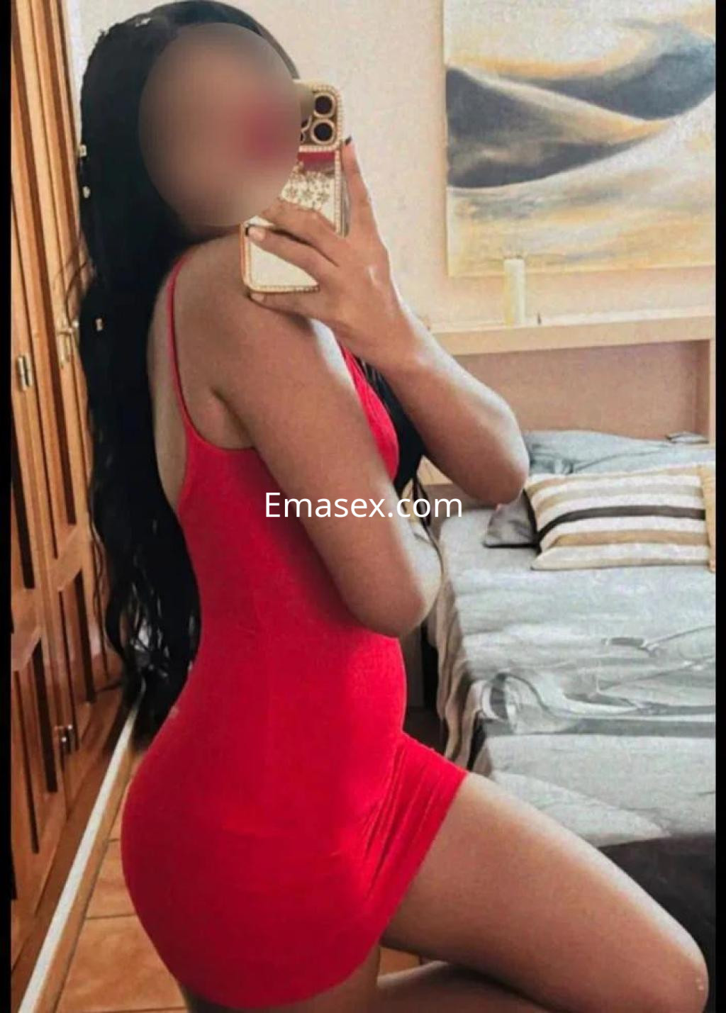 Escort en Pontevedra, con cabello largo y lacio, viste un vestido rojo ajustado y posa en un dormitorio.
