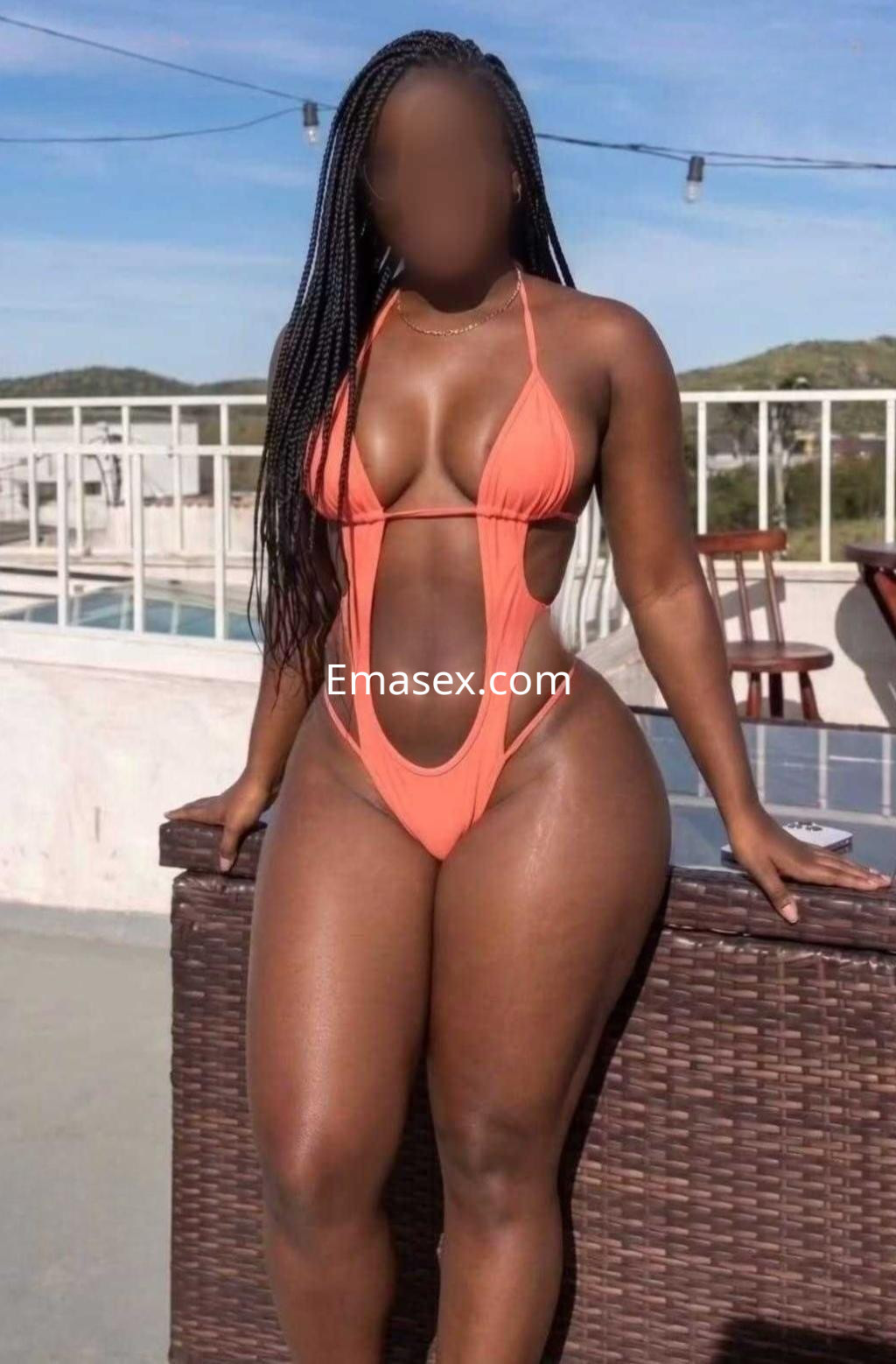 Puta de piel morena con trenzas, viste un bikini naranja en una terraza con piscina en Vigo.