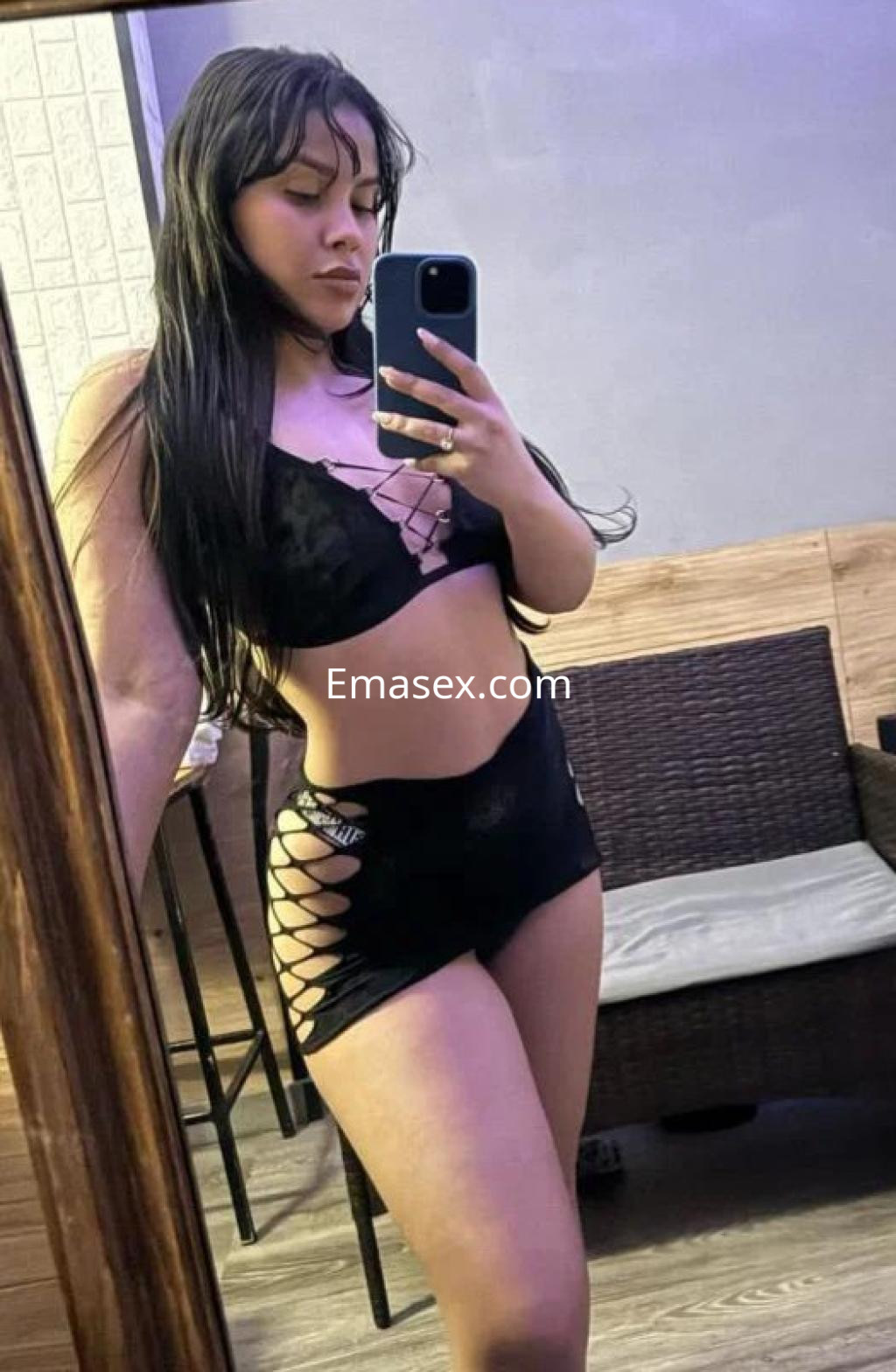 Escort en Cádiz posando frente a un espejo, con lencería negra y un peinado de cabello largo y lacio.