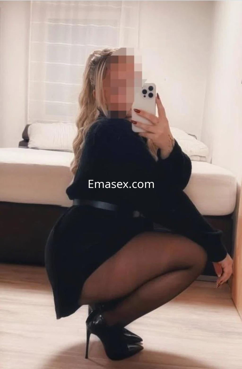 Escort en Zamora con cabello rubio, vestida con un suéter negro y tacones, posando frente a un espejo.