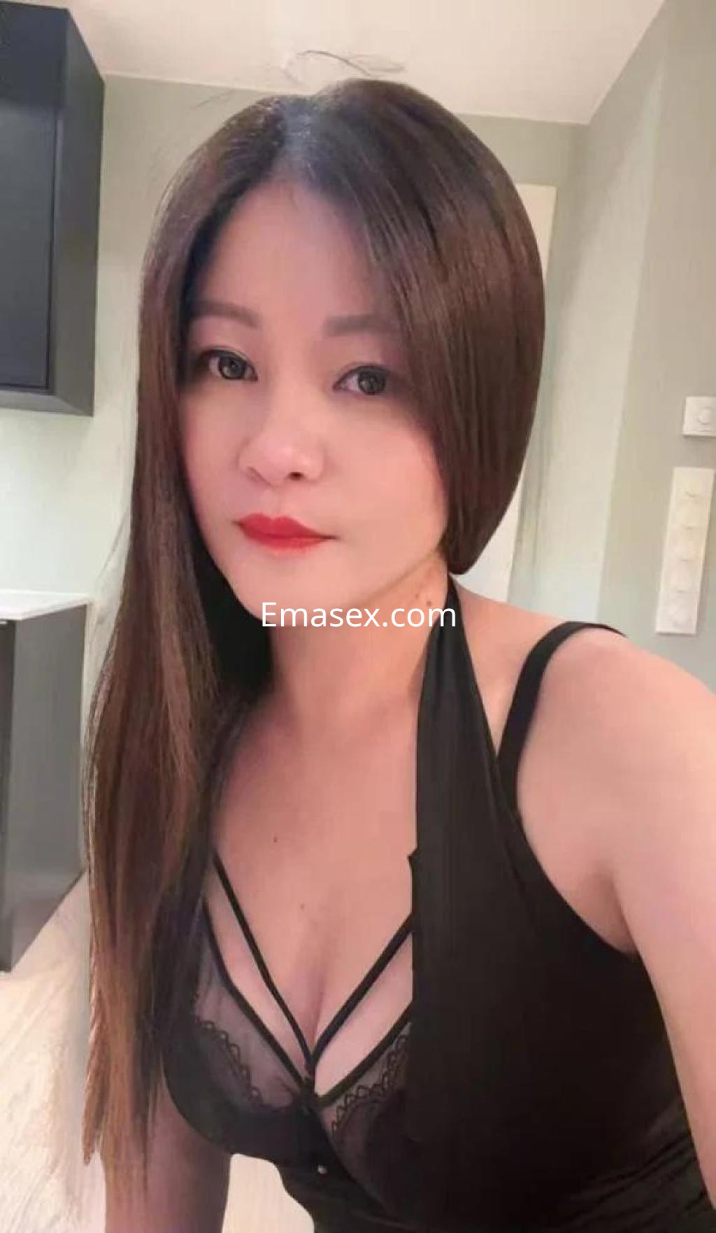 Escort en Lleida con cabello largo y lacio, vistiendo un top negro y lencería, posando en un entorno interior.