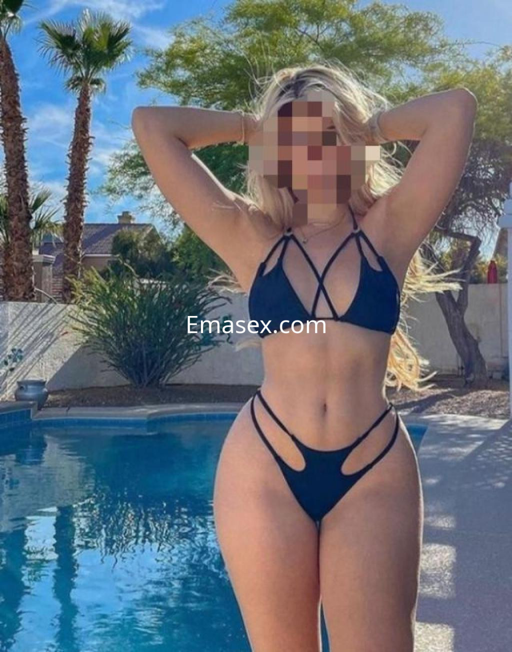 Puta en Tarragona muestra su figura en un bikini negro junto a una piscina, con palmeras al fondo.