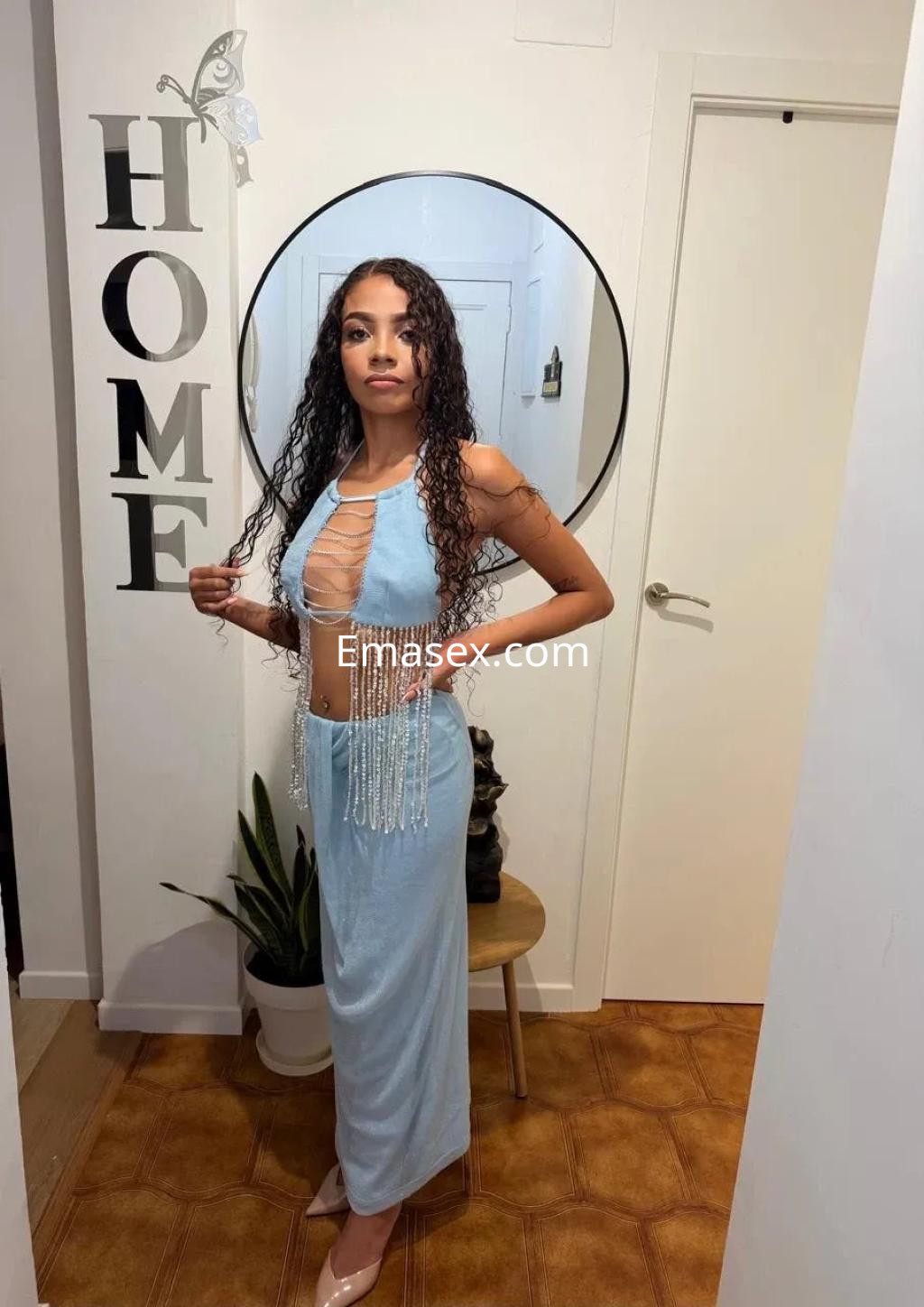 Escort en Zaragoza luciendo un vestido azul claro con detalles brillantes, en un ambiente acogedor y moderno.