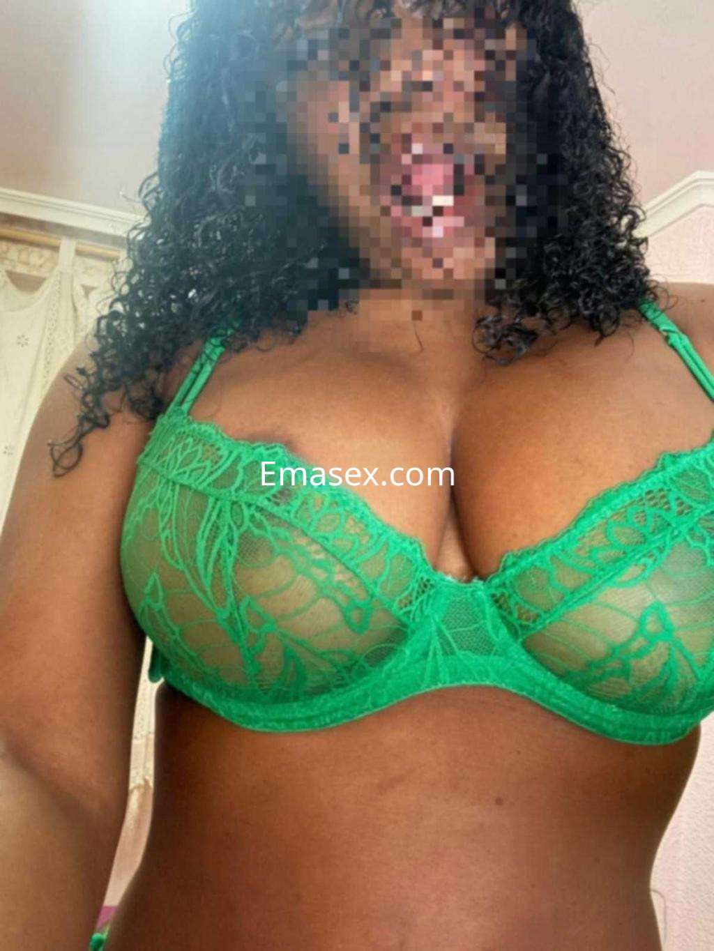 Escort en Zaragoza con cabello rizado y oscuro, vistiendo un sujetador verde transparente que resalta su figura.