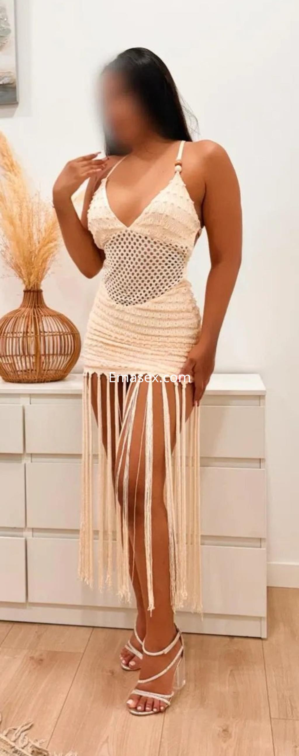 Escort en Palma de Mallorca, luciendo un vestido de hilo claro con flecos y sandalias de tacón alto.
