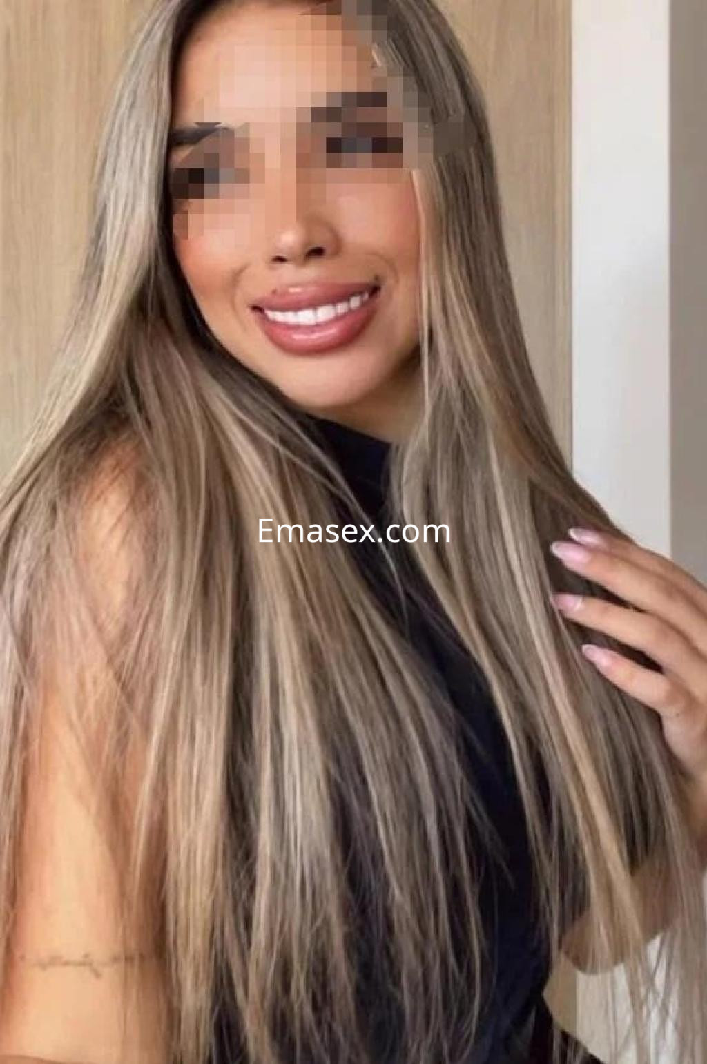 Escort en Tarragona con cabello largo y lacio de color castaño claro, vistiendo una blusa negra y sonriendo.