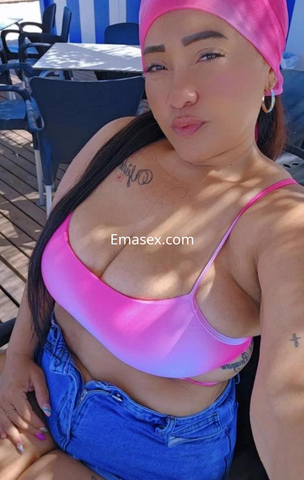 Escort en Castellón con un top rosa y pantalones cortos de mezclilla, posando en un ambiente al aire libre.