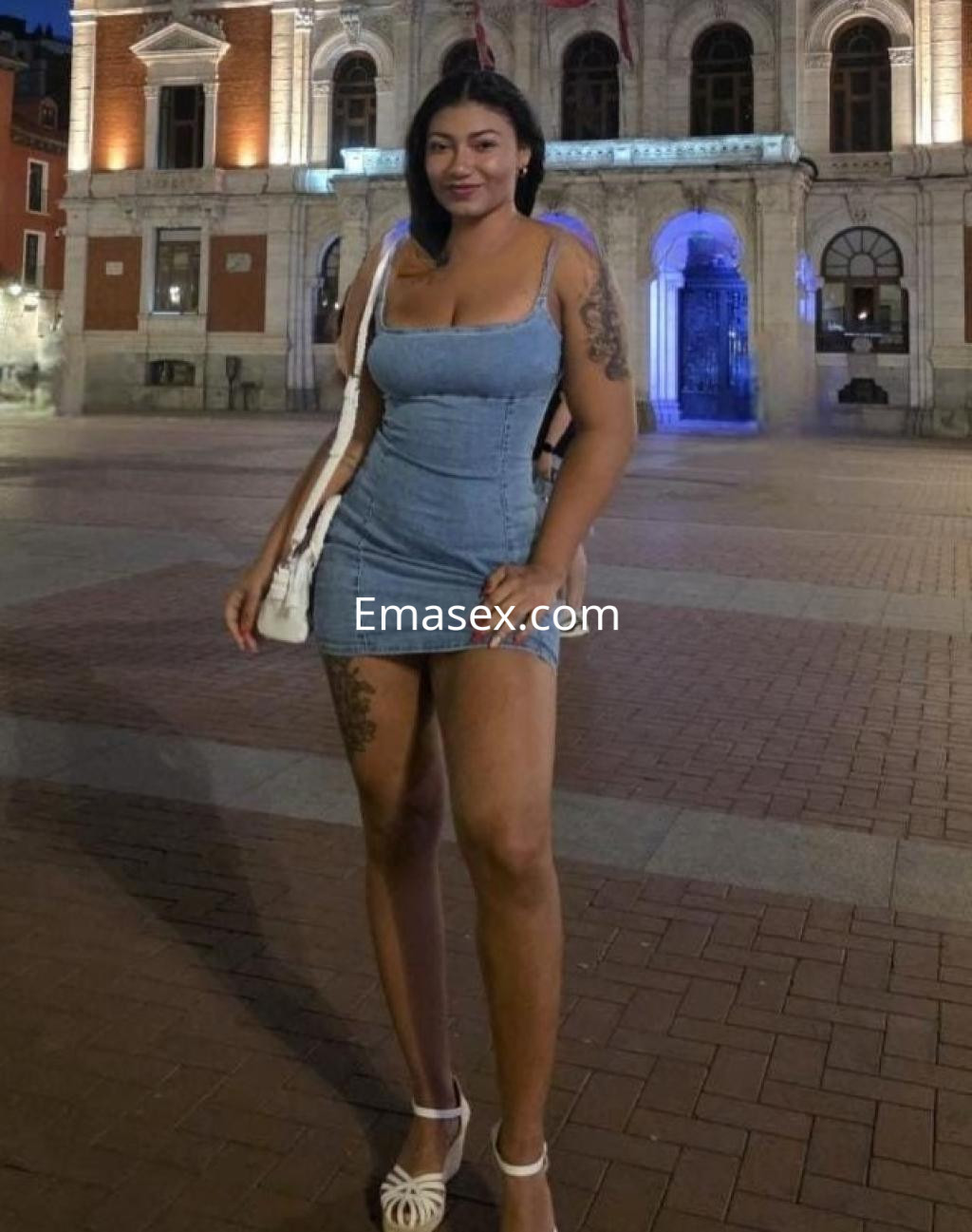 Puta posando en la plaza de Valladolid, luciendo un vestido corto de mezclilla y sandalias blancas.