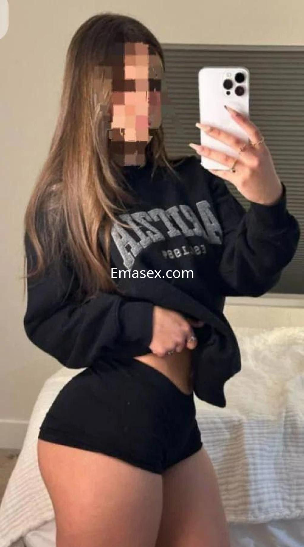 Escort en Barcelona con cabello largo y lacio, vistiendo sudadera negra y pantalones cortos, posando para la cámara.