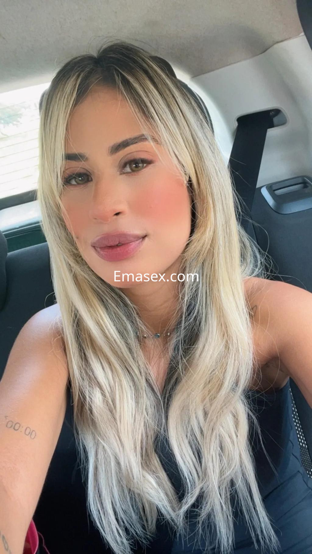 La escort en Murcia muestra una sonrisa mientras se toma una selfie en el interior de un coche.