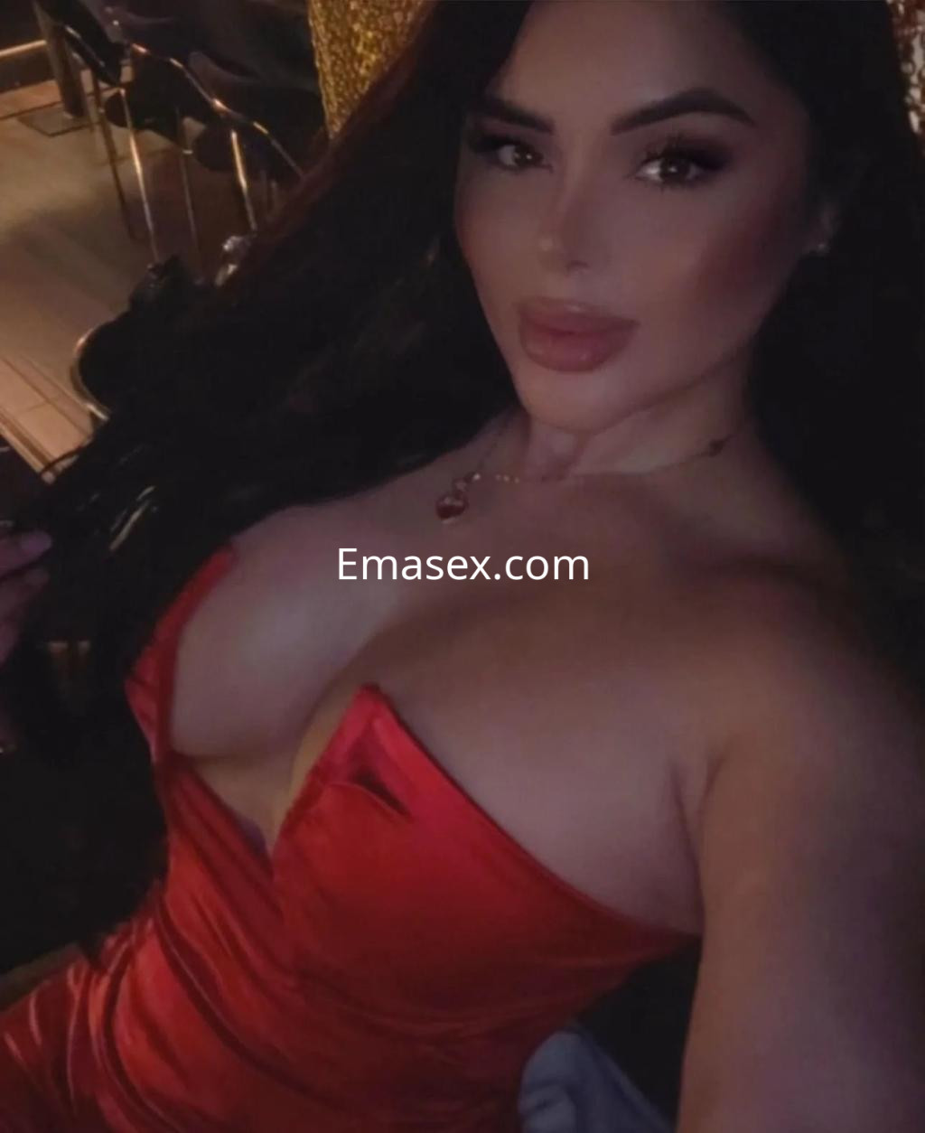 Escort en Valencia con cabello largo y oscuro, vistiendo un vestido rojo ajustado, posando con una expresión seductora.
