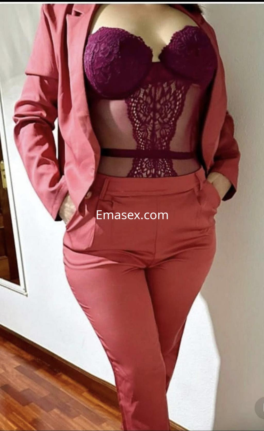 Escort en Donosti luce un traje rosa con un top de encaje burdeos, mostrando una pose elegante en un ambiente interior.