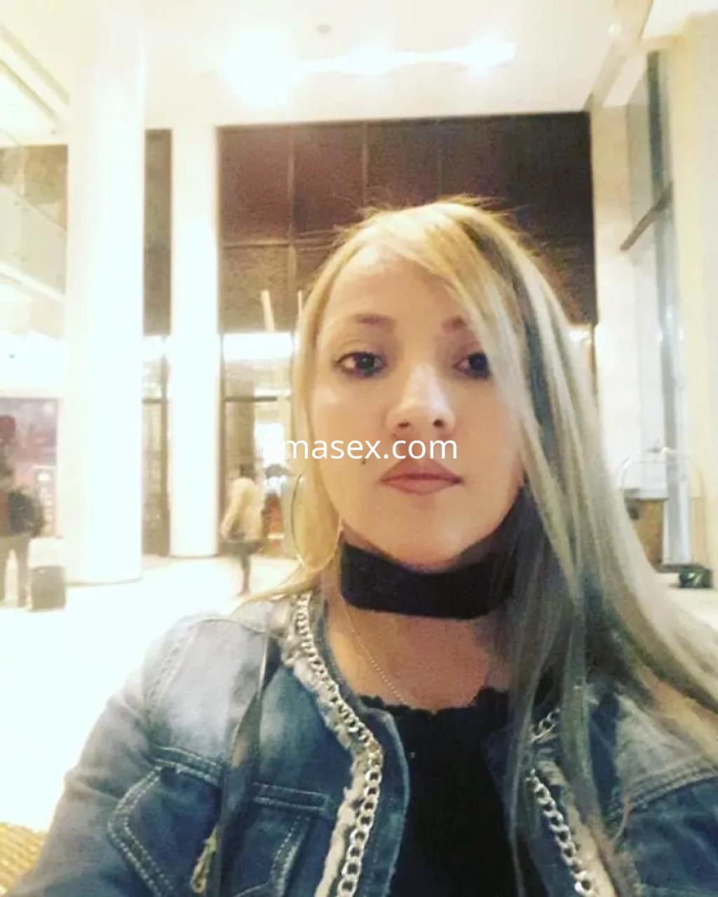 Puta con cabello largo y rubio, vestida con chaqueta de mezclilla, posando en un elegante vestíbulo en Alicante.