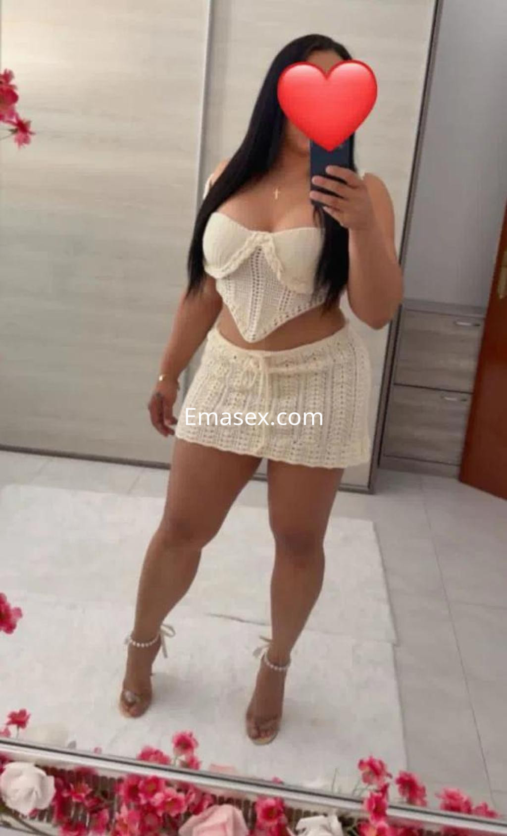 Puta posando en Badajoz con un conjunto de lencería blanco y tacones, mostrando una figura esculpida y cabello largo.
