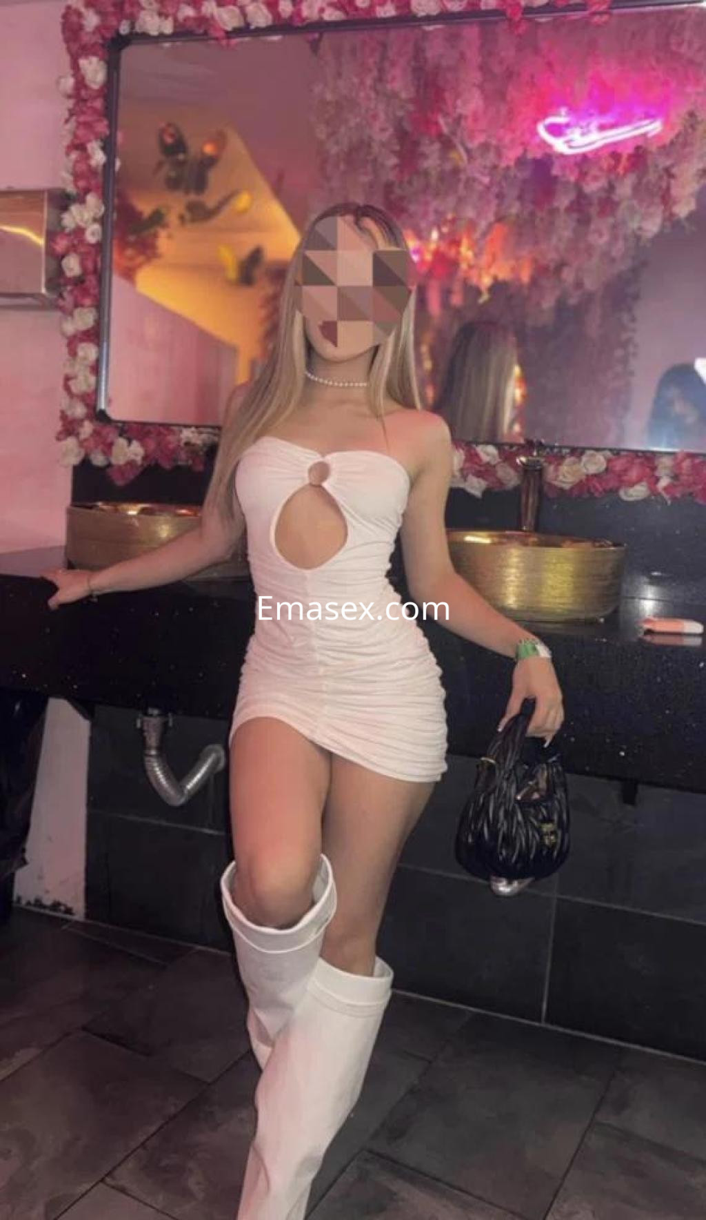Puta en Girona, posando con un vestido blanco ajustado y botas altas, en un ambiente de discoteca.