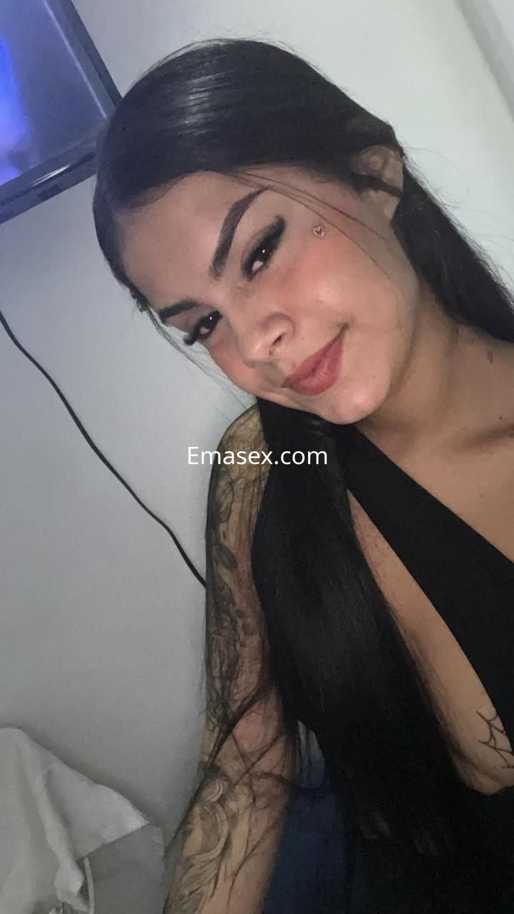 La puta de Zaragoza posa sonriendo, con cabello largo y lacio, luciendo un vestido negro y tatuajes visibles.