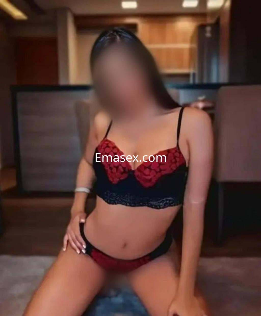 Escort en Bilbao posando con lencería negra y roja, en un ambiente moderno y acogedor.