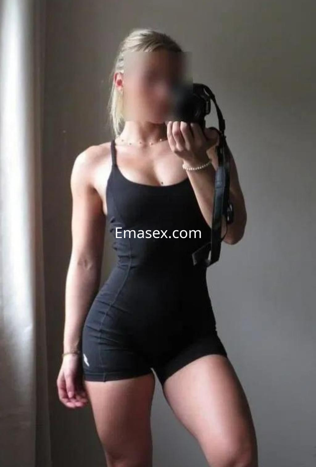 La puta muestra su figura atlética en un ajustado mono negro, posando en un entorno interior en Palma de Mallorca.