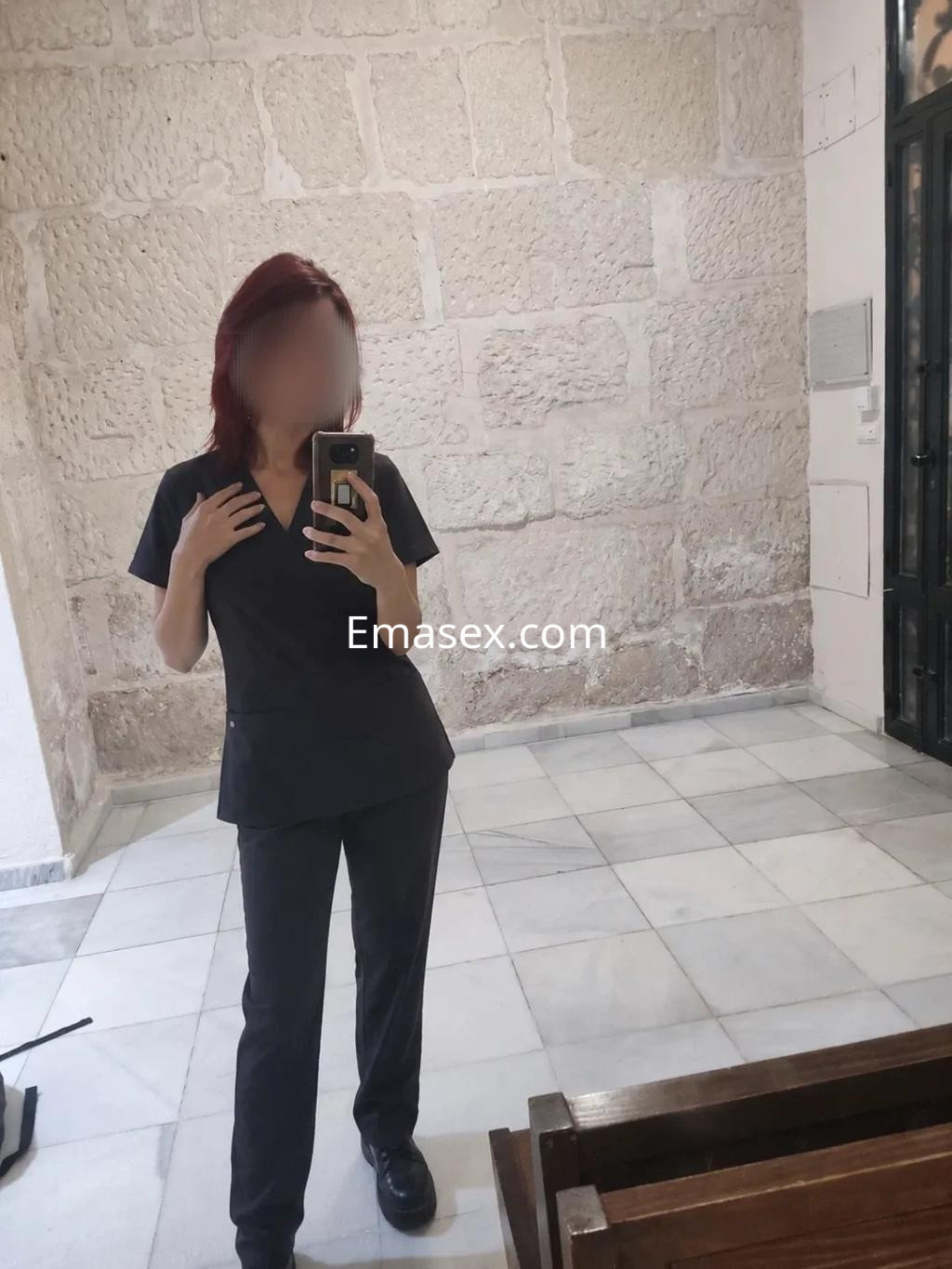 Puta con cabello rojizo, viste uniforme negro y se encuentra en un entorno interior de Alicante.