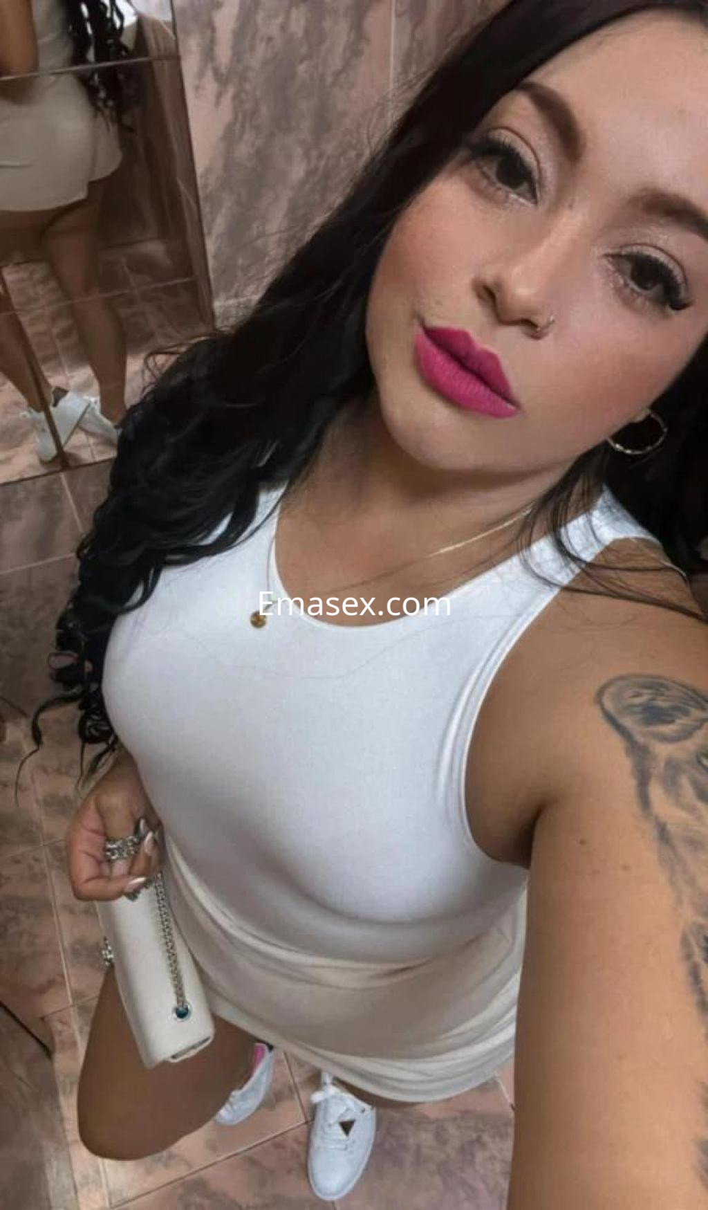 La puta en Barcelona posa con un vestido blanco ajustado y labios rosas, mostrando su cabello largo y rizado.