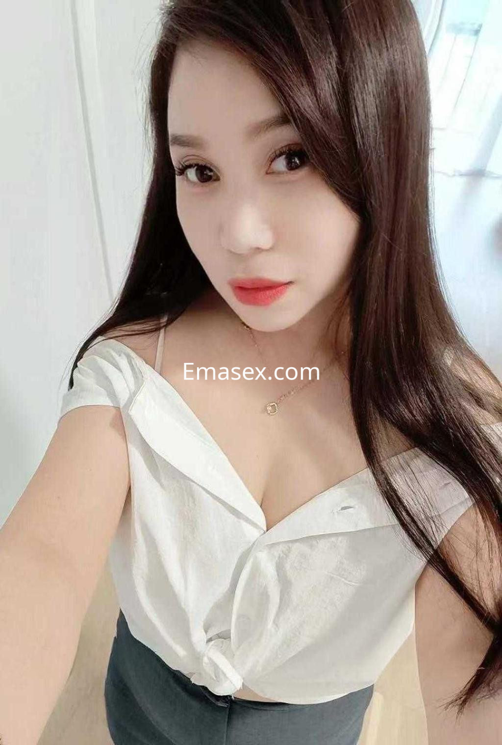 Puta en Barcelona con blusa blanca ajustada y falda oscura, mostrando una mirada seductora y cabello largo.