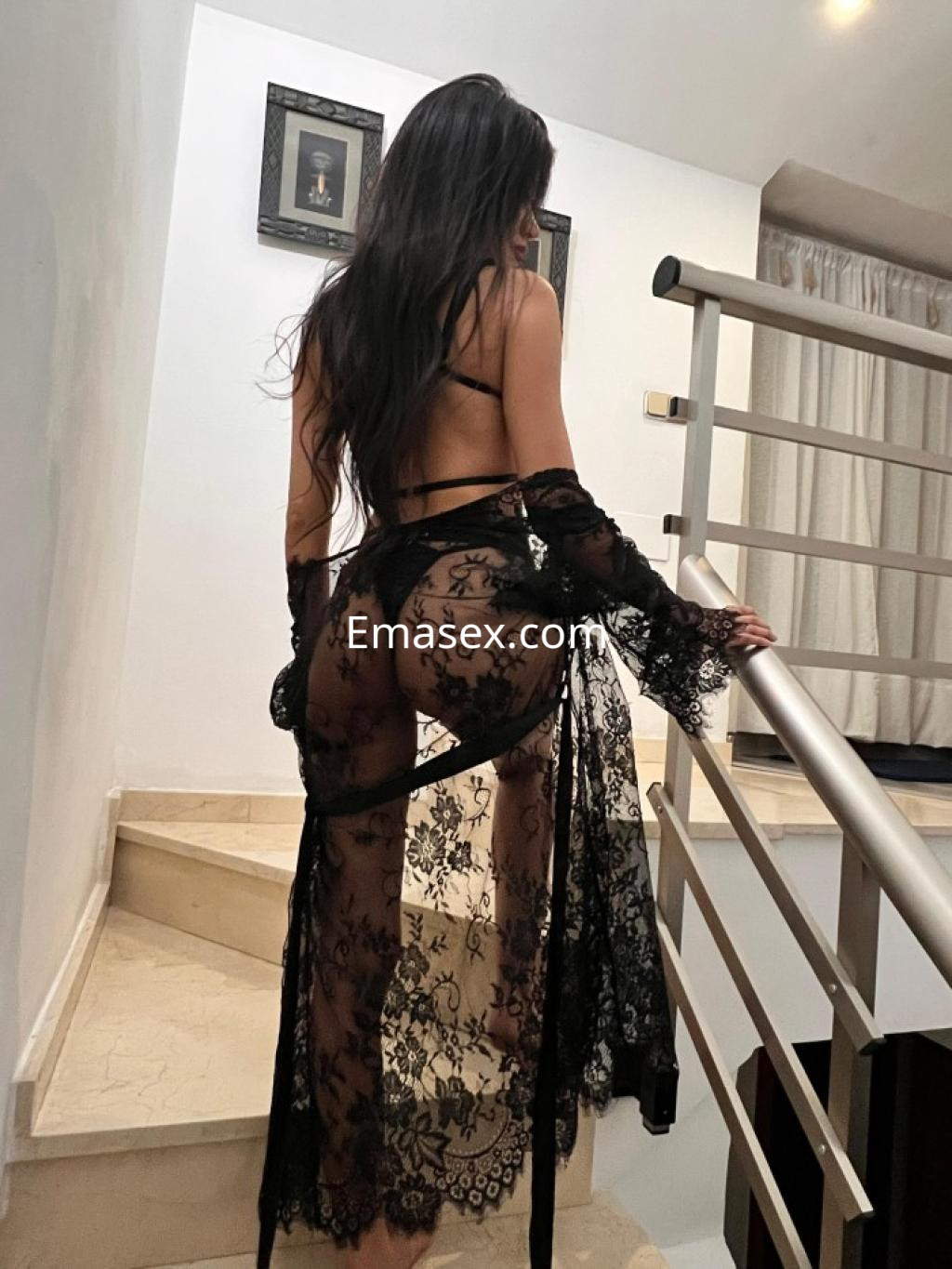 Puta de espaldas en Tarragona, vistiendo un vestido de encaje negro que deja entrever su figura.