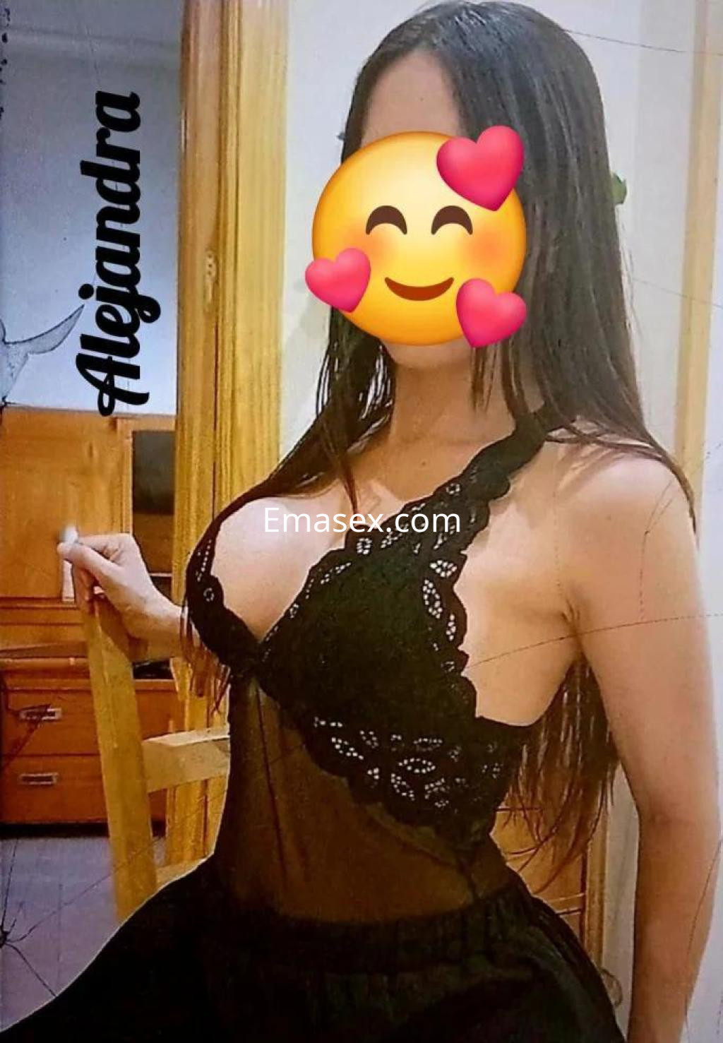 Escort en Toledo con vestido negro transparente que realza su figura, posando en un entorno doméstico.