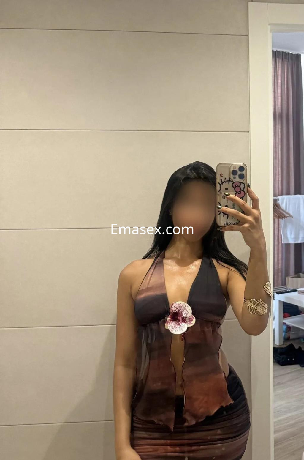 La puta en Valencia lleva un vestido transparente de tonos marrón y negro, posando frente a un espejo.