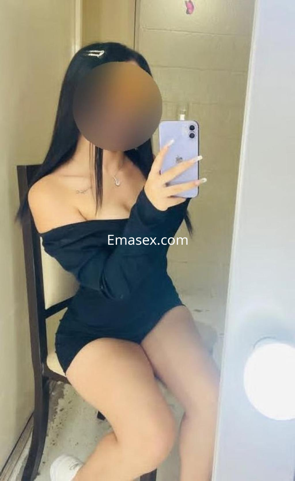 Escort en Valladolid con cabello lacio y largo, viste un vestido negro de tirantes mientras se toma una selfie.