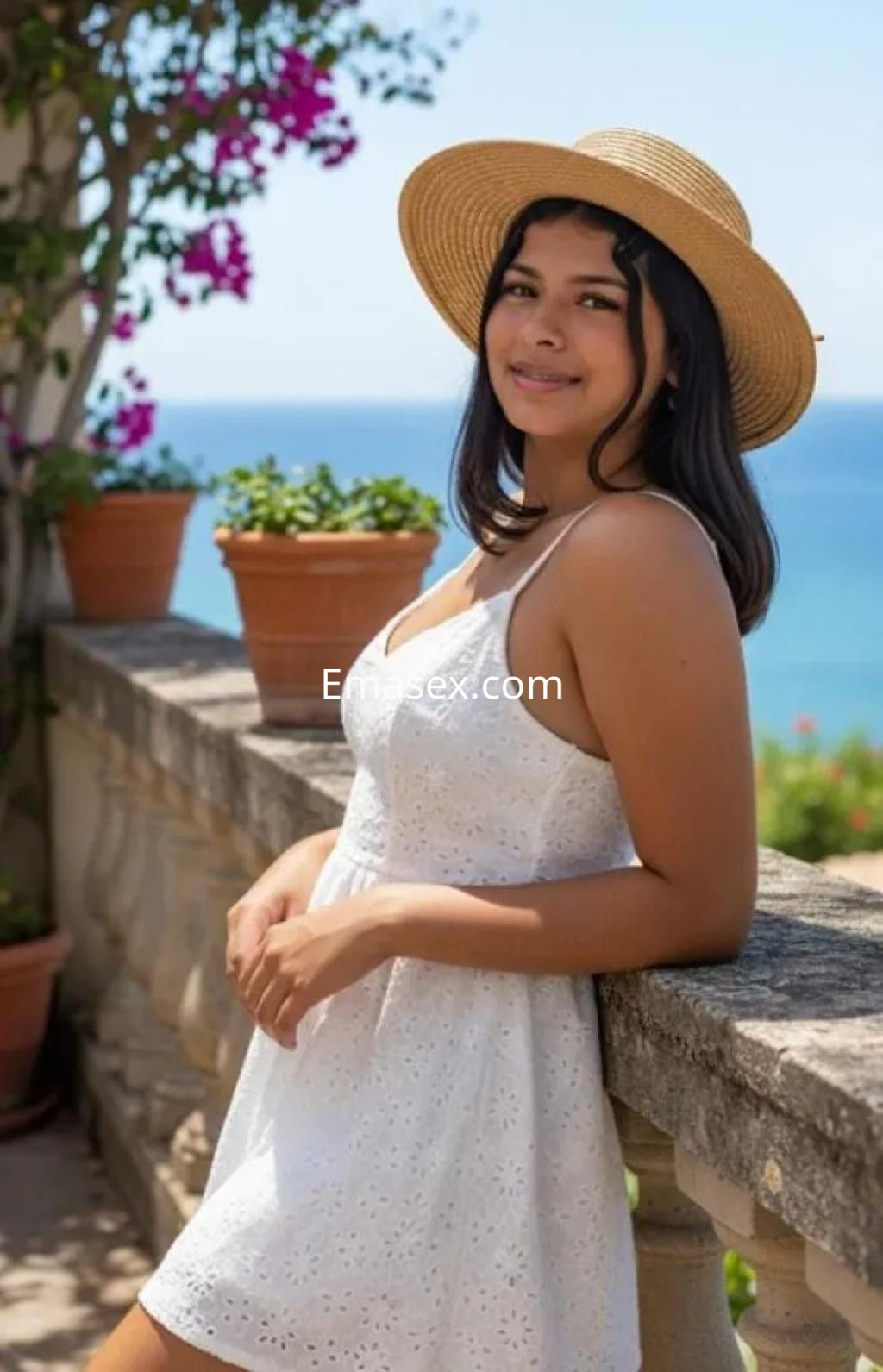Escort en Zaragoza, con vestido blanco y sombrero de paja, sonríe en un entorno al aire libre junto al mar.