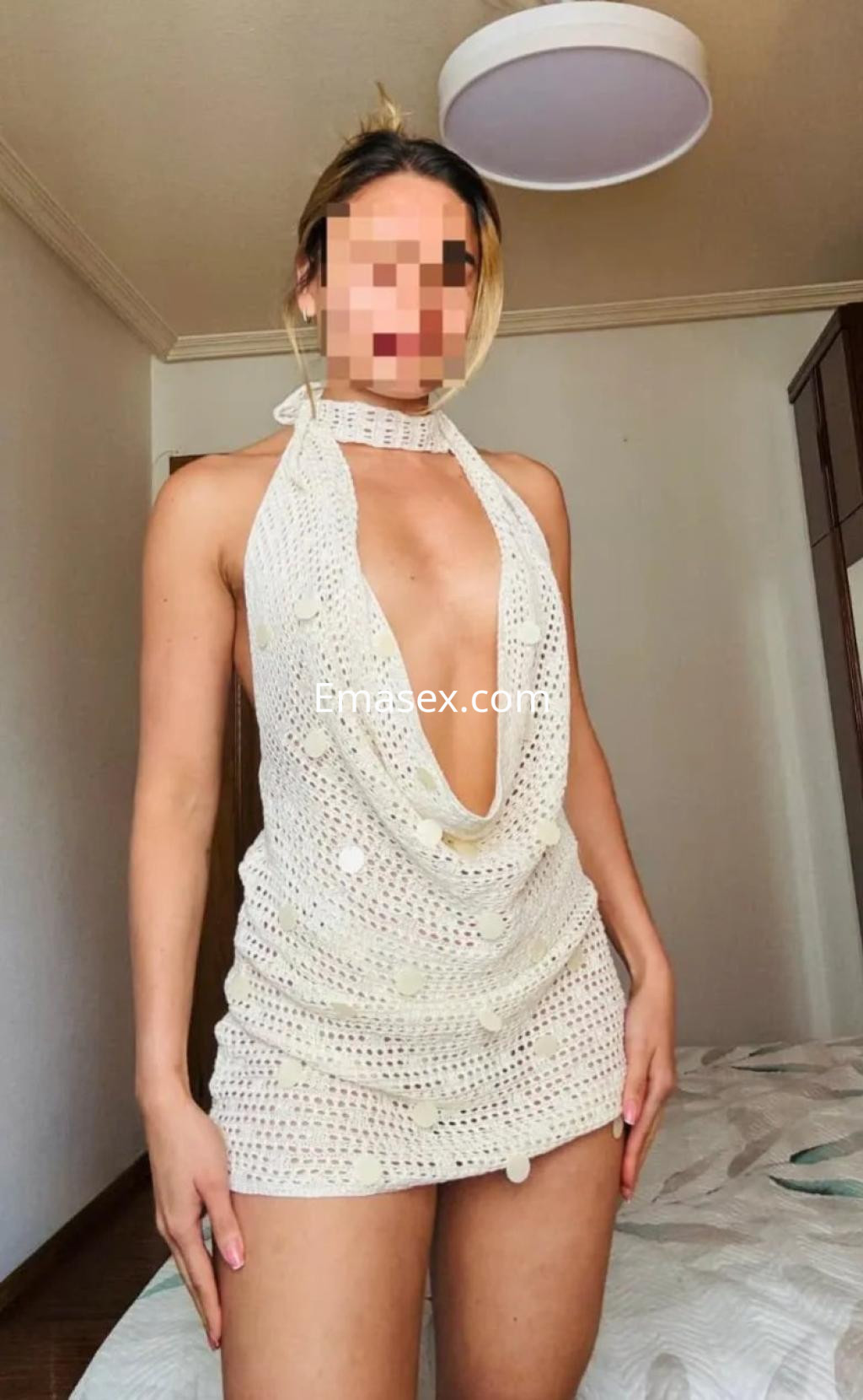 Puta en Gijón, vistiendo un vestido de red blanco con un escote pronunciado y cabello rubio.