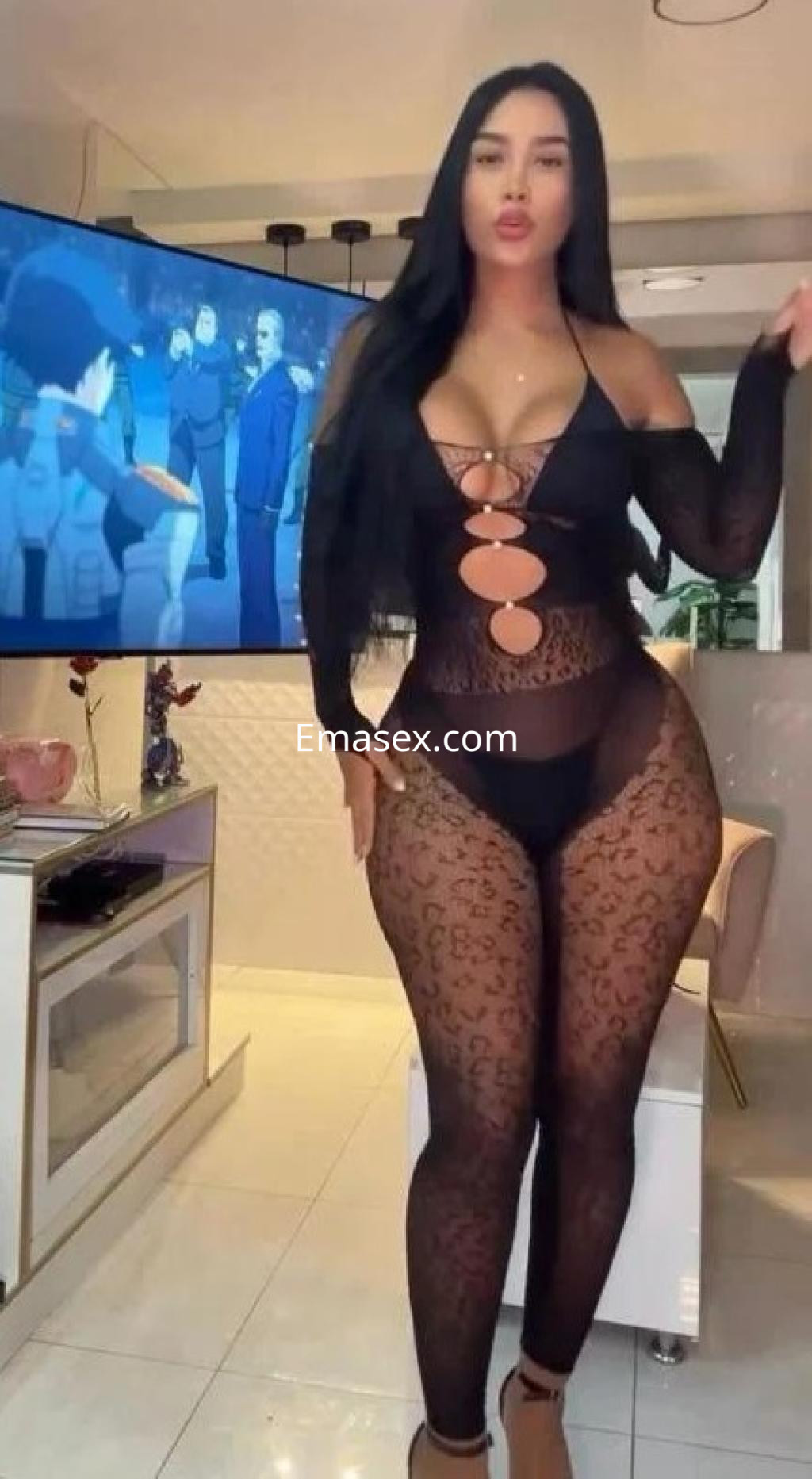 Escort en Barcelona, luciendo un bodysuit negro transparente con estampado de leopardo y un fondo moderno.