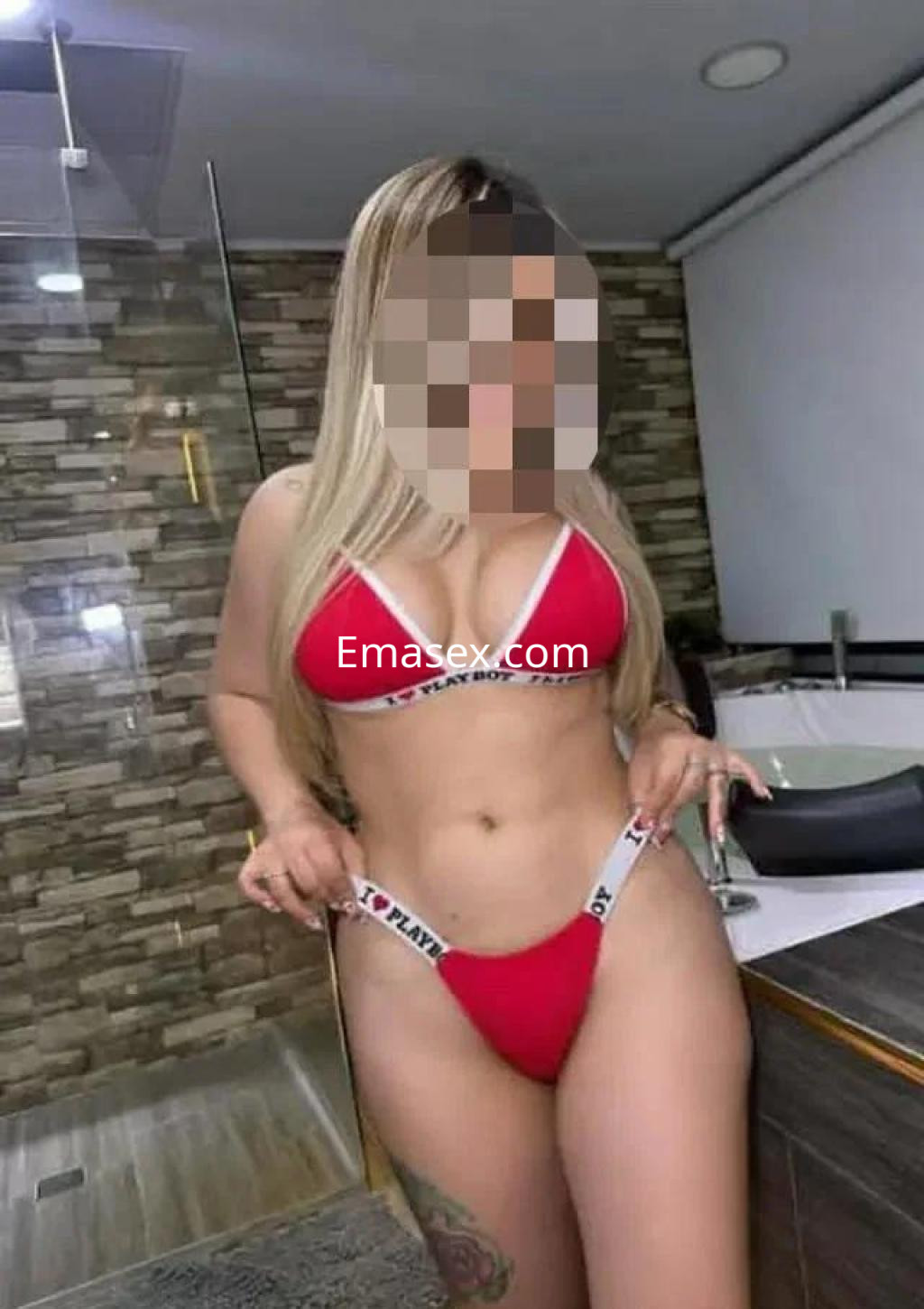 Puta en Albacete, posando en lencería roja con detalles en blanco, en un baño moderno y luminoso.