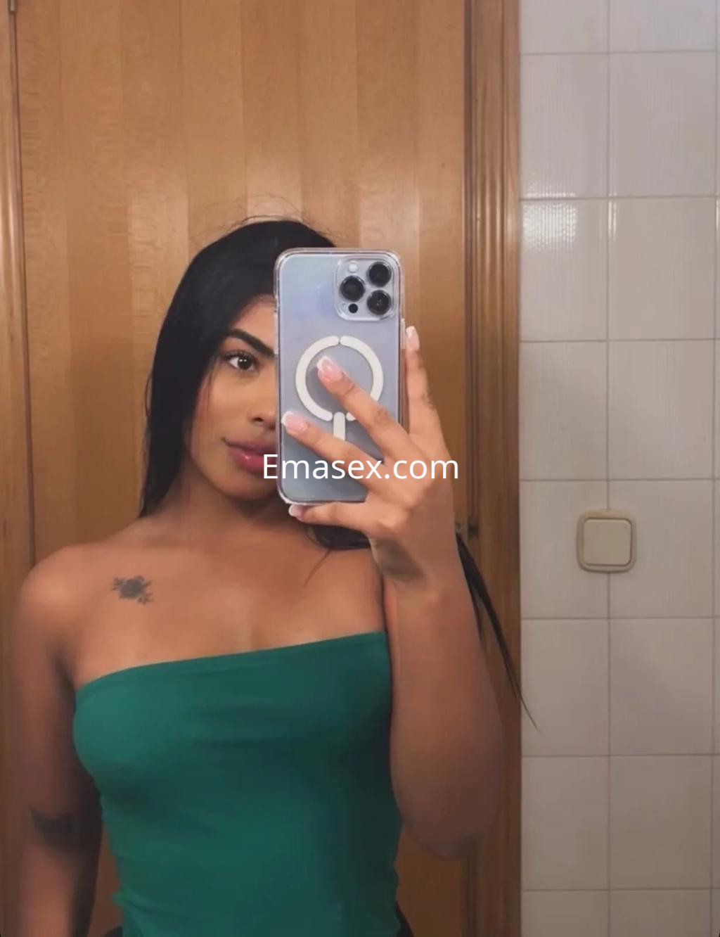 Puta en Alicante, con cabello largo y oscuro, viste un top verde y se toma un selfie frente a un espejo.