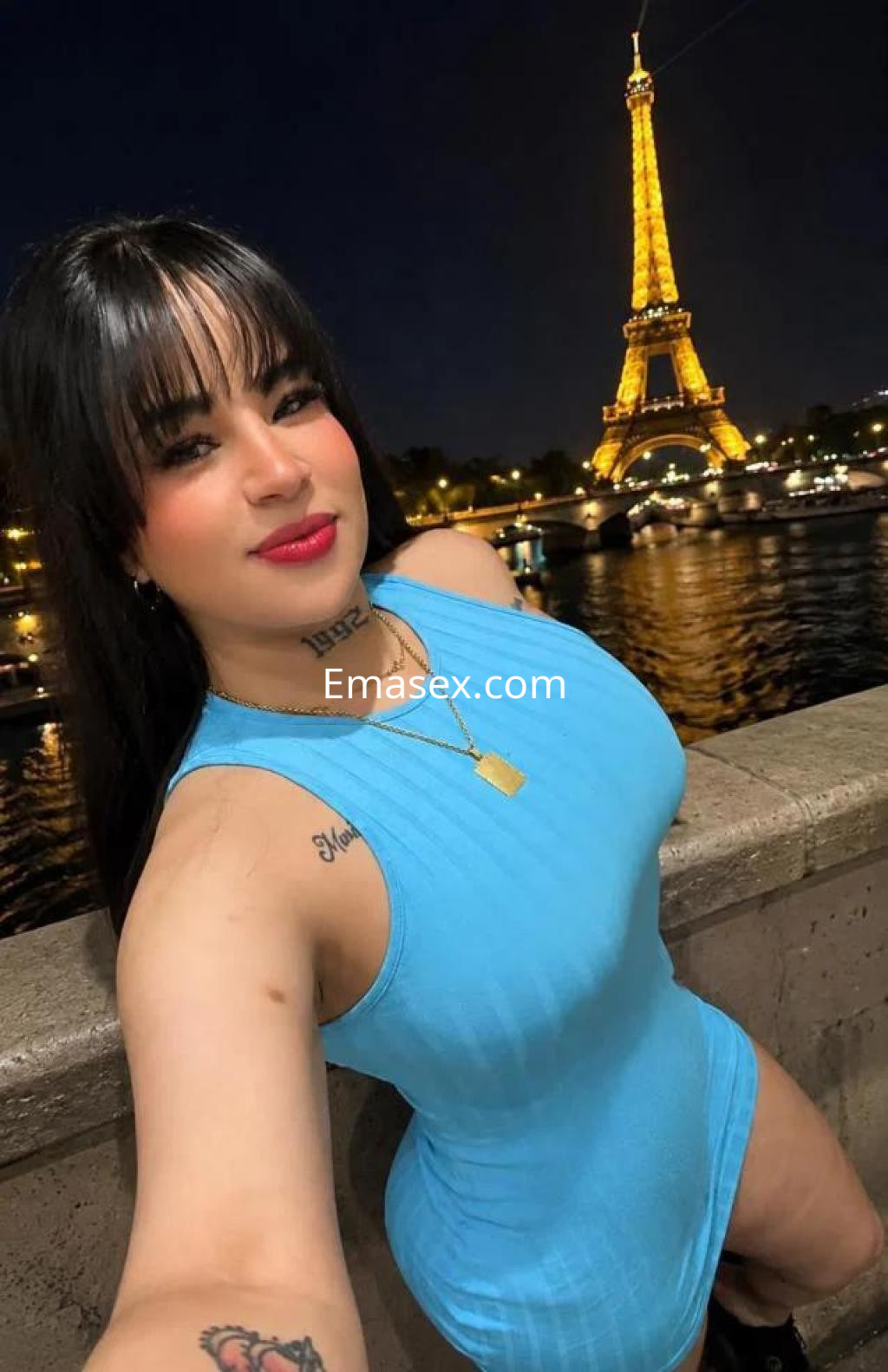 Puta posando en un vestido ajustado de color azul frente a la Torre Eiffel iluminada en París.