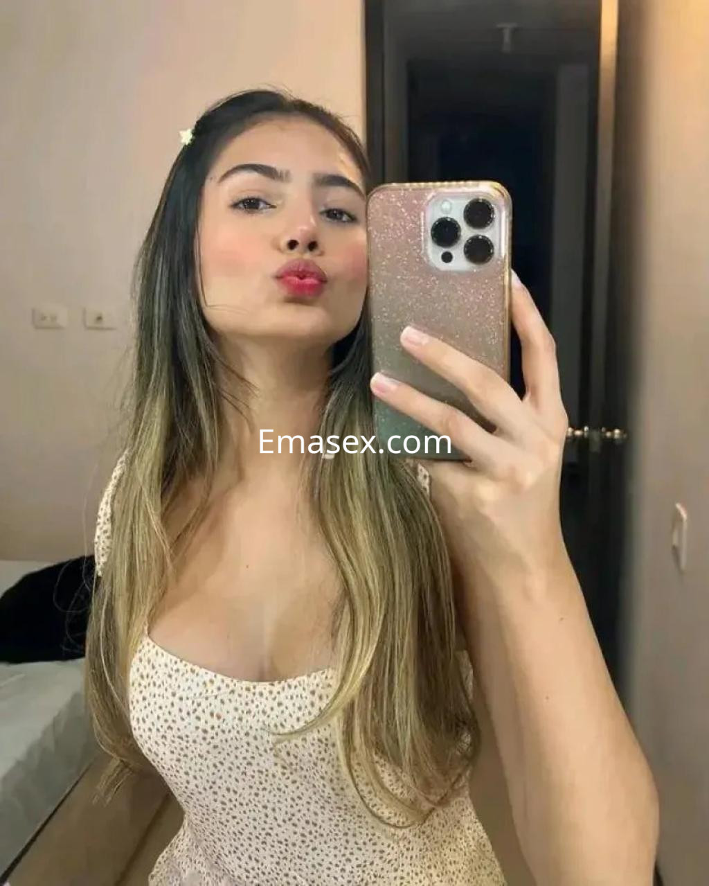 Puta de cabello largo y lacio, con un vestido claro, posando frente al espejo en una habitación de Málaga.